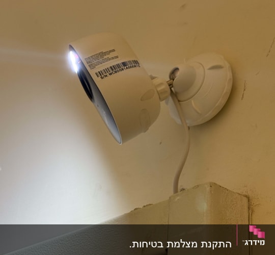 מצלמת אבטחה מותקנת על קיר עם כבל חשמל
